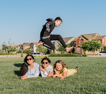 boy jumping over three girls on a field