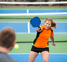 woman hitting a ball with a paddle on a court