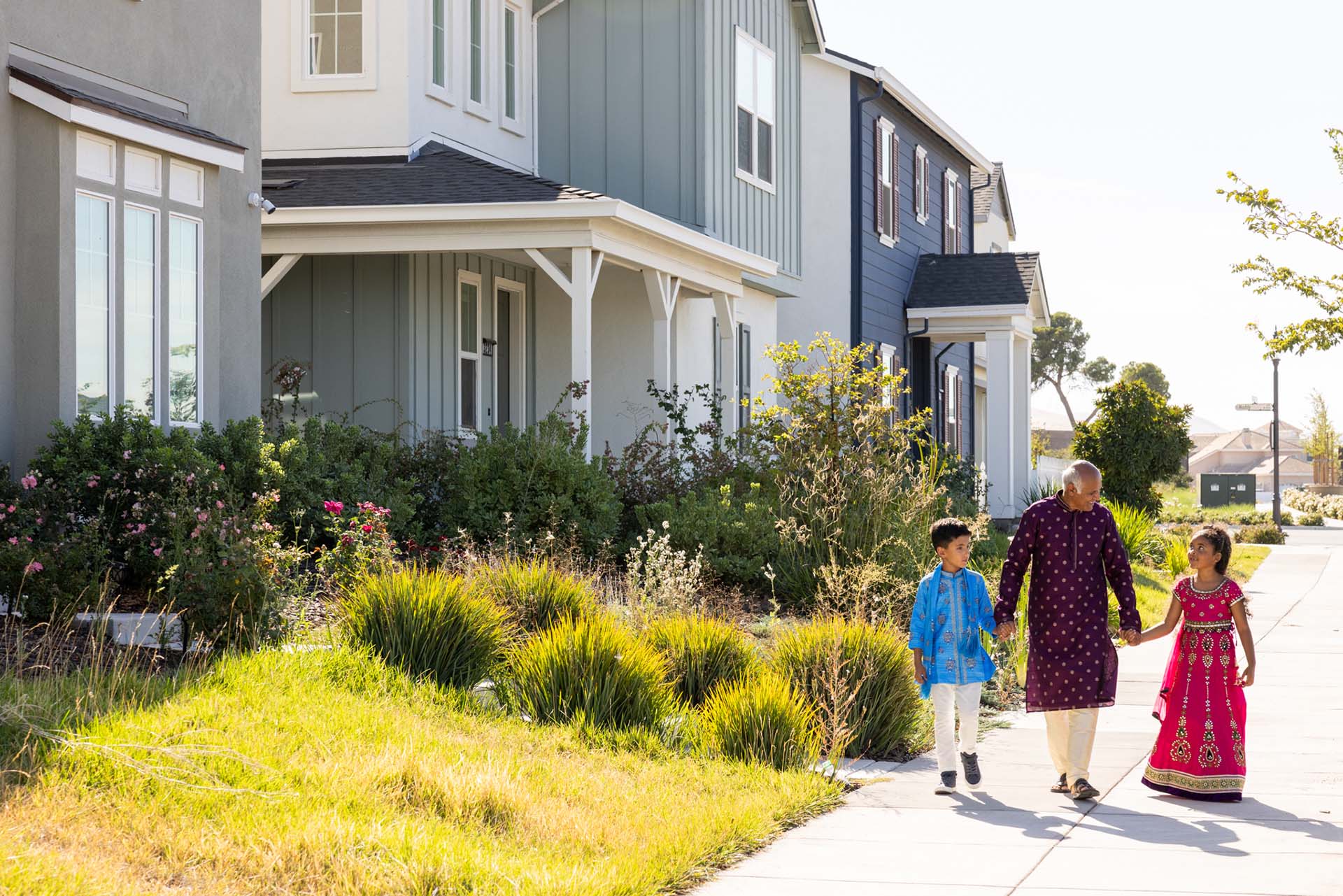 A grandfather walks holding hands with his grandchildren