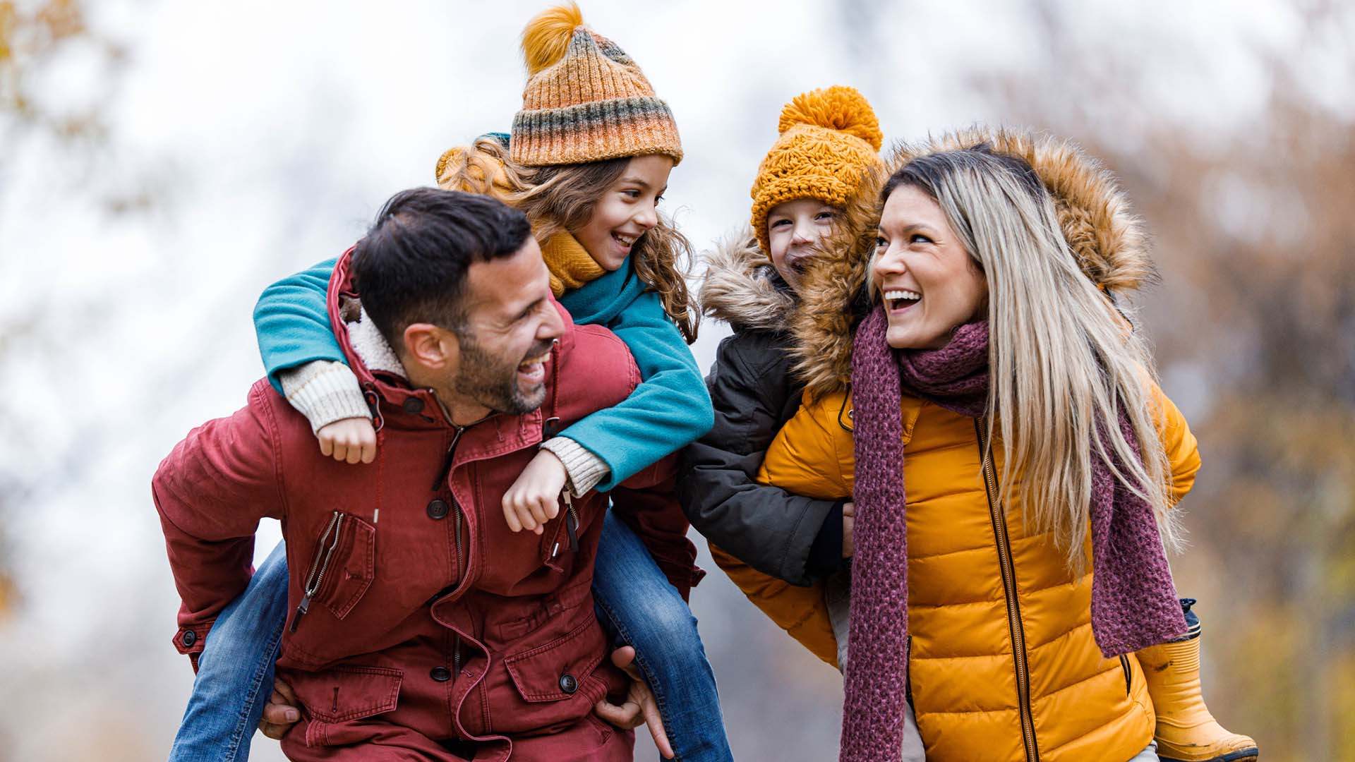 mother and father give piggyback rides to their daughters